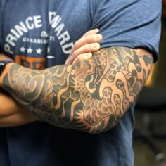 a man with a dragon tattoo on his arm is holding his arms crossed in front of him