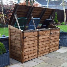 a large wooden storage box with two green trash cans in it's back yard