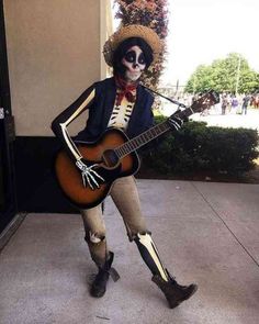 a skeleton playing a guitar on the sidewalk