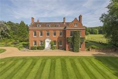 an aerial view of a large red brick house in the middle of a lush green field