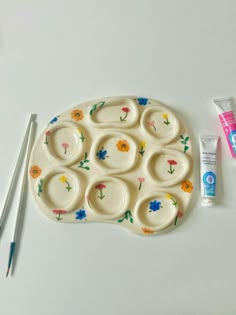 a white tray with flowers painted on it next to toothbrushes and other items