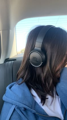 a woman wearing headphones in the back seat of a car