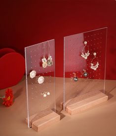 two clear acrylic displays with flowers and pearls on them next to a red vase