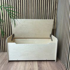 a wooden storage box sitting on top of a hard wood floor next to a plant