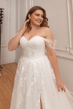 a woman in a wedding dress posing for the camera with her hand on her hip