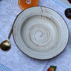 a white plate with an orange and spoon next to it on a blue table cloth