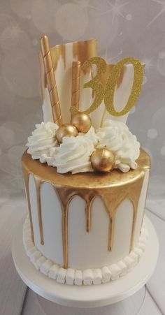 a white cake with gold decorations and the number 30 on top is sitting on a table