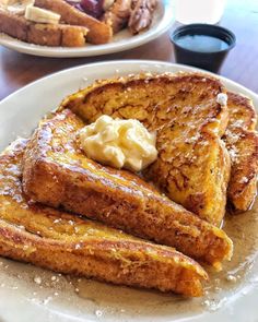 french toast with butter and syrup on a white plate next to other plates of food