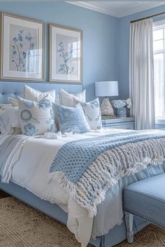 a bedroom with blue walls and white bedding in the center, two framed pictures on the wall