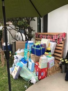 a pile of presents sitting under an umbrella on the grass next to a bench and table