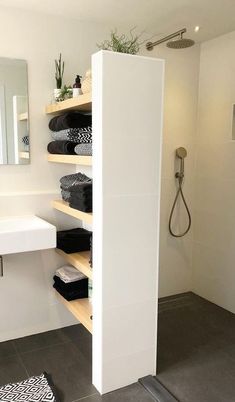 a white bathroom with black and white rugs on the floor next to shelves filled with towels