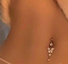 the back of a woman's stomach wearing a gold and white flower belly ring