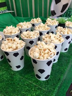 several cups filled with popcorn sitting on top of a green table covered in fake grass