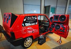 a small red car with speakers on it's back end and the door open