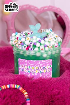 a jar filled with lots of candy sitting on top of a pink blanket next to a mirror