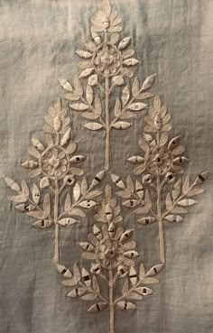 an embroidered piece of cloth with flowers and leaves