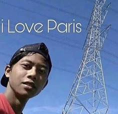 a young man standing in front of a tower with the words i love paris on it