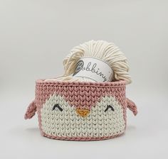 a crocheted basket with a bird face on the side and yarn in it