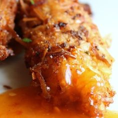 two pieces of fried food sitting on top of a white plate covered in gravy