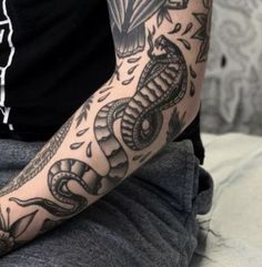 a man's arm with tattoos on it and a snake in the middle of his arm