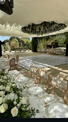 an outdoor dining area with tables, chairs and white flowers on the tablecloths