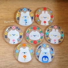 four glass magnets with animals on them sitting on top of a wooden table next to each other