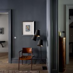 a chair sitting next to a lamp on top of a wooden floor in a living room