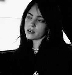 a woman sitting in the back seat of a car looking off into the distance with her eyes closed