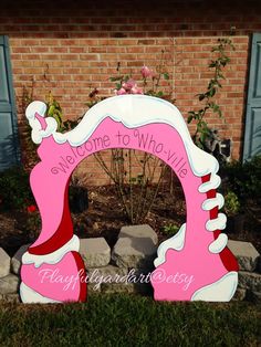 a pink and white shoe shaped sign in front of a brick building