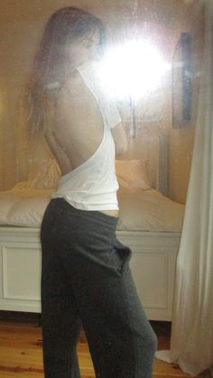 a woman standing in front of a mirror with her back turned to the camera,