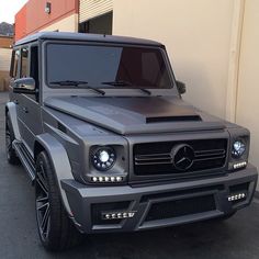 a mercedes g - class is parked in front of a building