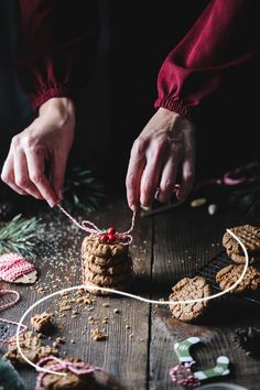 a person is decorating cookies with twine and candy canes on a wooden table