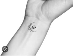 a black and white photo of a person's wrist with a dog paw tattoo on it