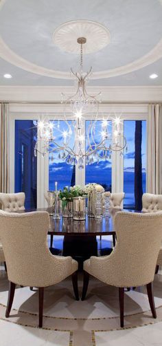 a formal dining room with chandelier and chairs in front of a large window