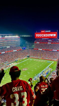 a stadium filled with lots of people watching a football game on the field at night