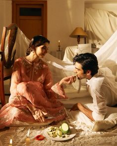 a man and woman sitting on the floor eating food