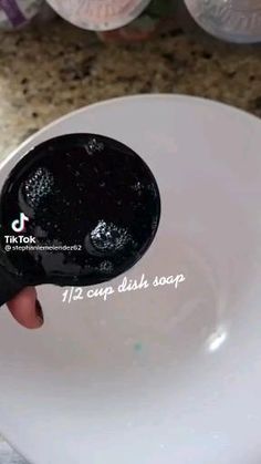 a person is holding a spoon with black liquid on it in front of a sink