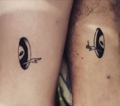 two people with black and white tattoos on their legs, one has an eyeball