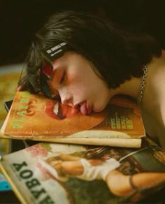 a young man sleeping on top of a book with his head resting on an open magazine