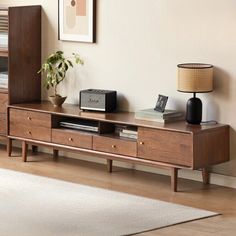 a living room with a tv stand, bookshelf and lamp on the floor