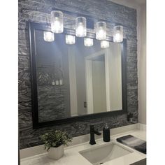 a bathroom with a sink, mirror and lights on the wall above it's counter