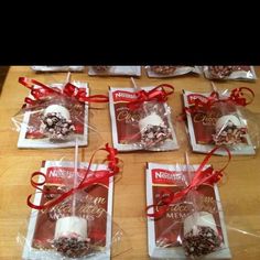 six bags of cookies wrapped in cellophane and tied with red ribbon on a table