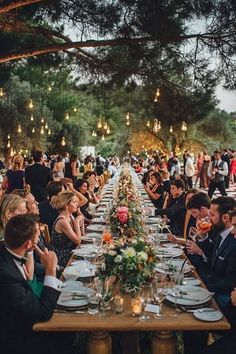 a group of people sitting around a long table with plates and glasses in front of them