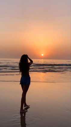 a woman standing on top of a beach next to the ocean