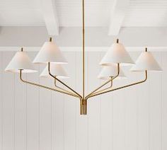 a chandelier hanging from the ceiling in a room with white walls and wood paneling