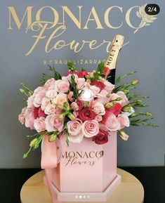 a pink box filled with flowers and a bottle of champagne on top of a table