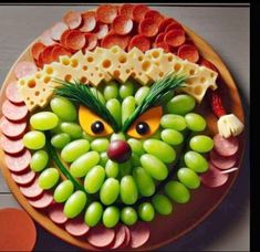 a plate that has grapes, cheese and ham on it with an owl face made out of them