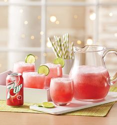 pitcher and glasses filled with watermelon soda on a tray next to lime slices