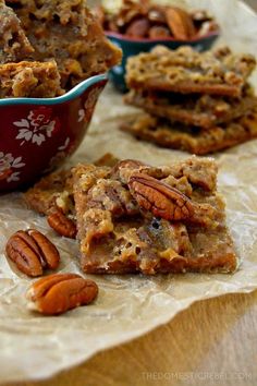 several pieces of pecan bars are on a table next to a bowl of pecans