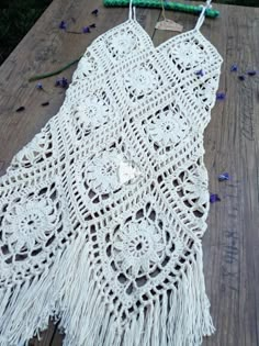 a crocheted doily on a wooden table with beads and flowers around it